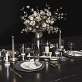 Elegant Dinnerware Set with Black Plates Gold Cutlery Wine Glasses Candle Holders and Flower Bouquet