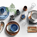 Stylish Dinnerware Set With Ceramic Plates Blue Bowls Wooden Trays Metal Utensils And Green Leaves