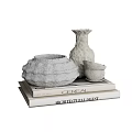 Decorative Ornament Set Featuring Shell Shaped Container Tall Vase and Small Cup on Stacked Books