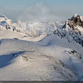 Snowy Mountain Peak With Snow Covered Slopes Rocky Outcrops Under Clear Blue Sky