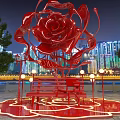 Giant Red Rose Sculpture Illuminated At Night With City Skyline And People Around