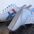White Shoes With Blue And Red Stripes White Laces Brown Textured Sole With Grid Pattern