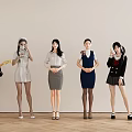 Women In Different Outfits Standing And Sitting Against Light Colored Wall With Wooden Floor
