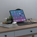 Tablet with Keyboard on Wooden Desk Workspace Including Potted Plant Mouse Earbuds and Books