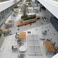 Commercial Street Outdoor Seating Area With Wooden Benches Green Plants And Stone Paved Floor
