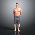 Shirtless Man Standing with Hands Behind Back in Gray Tight Pants on Gray Background