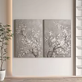 Two Gray Background Paintings With White Flower Branches And Green Plant Near White Shelf
