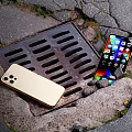 Gold iPhone And Modern Smartphone With Bright Screen Displaying Apps On Outdoor Surface