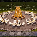 Scenic Campsite With Pyramid Shaped Wooden Structure White Chairs Tables And String Lights