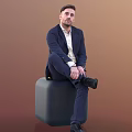A Man In Navy Suit White Shirt Sitting On Gray Cylindrical Stool Brown Background