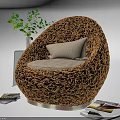 Woven Brown Round Leisure Chair with Light Colored Cushion Green Plant Transparent Vase and Magazines