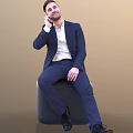 A Man In Dark Blue Suit White Shirt Sitting On Black Cube Talking On Phone