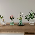 Different Shaped Glass Vases With Pink Flowers White Blooms And Greenery On Wooden Table