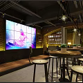 Modern Industrial Bar Interior With Large LED Screen Brick Wall Wine Rack And Round Tables