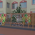 Colorful Playground Equipment With Spider Web Climbing Net And Rings By Wooden Fence Near School Building