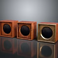 Three Square Wooden And Metal Speakers With Circular Drivers On Reflective Surface
