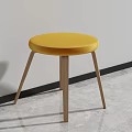 Round Yellow Stool with Upholstered Seat and Wooden Legs in Minimalist Interior with Gray Floor