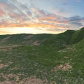 Stunning Colorful Sunset Sky Over Lush Green Rolling Grassy Hills Beautiful Outdoor Natural Landscape