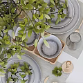 Stylish Tableware Set with Green Plants Wine Glasses Plates and Candle Holders on White Table