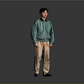 Man in Green Jacket and Beige Pants Standing with Headphones on Gray Background