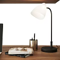 Modern Table Lamp with White Shade on Wooden Desk with Metal Pen Holder and Magazine
