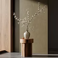 Light Gray Vase With White Blossom Branches On Wooden Cylindrical Stand Against Wooden Wall