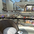 Modern Shopping Mall Atrium Interior Design With Wicker Chair Coffee Cup And Green Plants