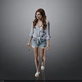 Woman in light blue shirt and denim shorts walking with sunglasses on gray background