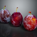 Three Vibrant Red Purple Plums With Frosty Bloom On Dark Reflective Background