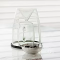Transparent Glass Container With Funnel Top Base And Metal Bowl Of Black Pebbles