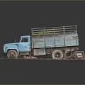 Old Blue Truck With Worn Body Loaded Green Plants On Gravel Ground