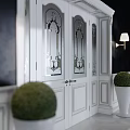Elegant White Entry Interior With Stained Glass Door Wall Lamps And Green Topiaries