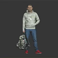 Man in Gray Hoodie Blue Jeans Red Shoes Holding Patterned Backpack Against Gray Black Background