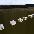 White Small Garden Structures Arranged on Green Grassland With Trees and Sky Background
