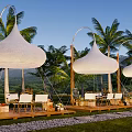 Camping Site with White Conical Tents Palm Trees Wooden Platforms Green Grass and Mountain Views