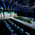 Stage With Blue Lighting Large Screen Seascape View Neatly Arranged White Chairs And Green Plants