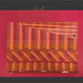 Red Square Clutch Bag With Orange Yellow Stripes And Gold Clasp On Black Surface