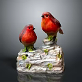 Red Bird Figurines Perched On White Base With Green Moss