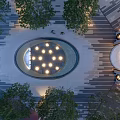Illuminated Circular Water Fountain With Surrounding Trees And Paved Plaza Ground