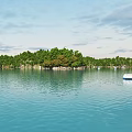 Scenic Garden Landscape on Island with Lush Green Trees and Blue Water Featuring White Yacht