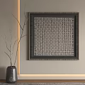Woven Square Artwork With Dark Frame And Gray Vase With Twigs On Light Wall