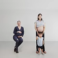 Two Pregnant Women And A Child Smiling Together In Studio Portrait