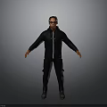 Man Wearing Sunglasses In Black Jacket And Pants Standing With Arms Outstretched Against Gray Background