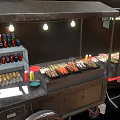 Grilled Skewers At Food Stall With Multiple Trays Red Chairs Black Tables And Condiment Bottles