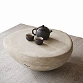 Round Stone Coffee Table With Black Teapot And Two Small Teacups On Woven Rug