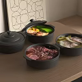 Three Black Casserole Pots With Various Foods Inside On Wooden Countertop