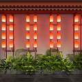 Traditional Red Lanterns Arranged on Wall with Lush Green Plants Below