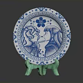 Blue and White Decorative Plate With Floral Border And Two Figure Designs On Green Stand