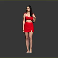 A woman in red dress with curly hair standing against gray background wearing high heels