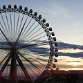 Ferris Wheel Amusement Ride With Sunset Sky And City Buildings View